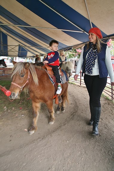 Image of child riding on a pony supervised by an adult.