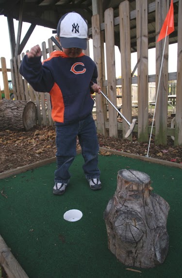 A child playing in the putt-putt section outside.