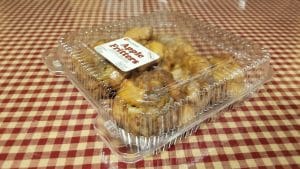 Image of four apple fritters in a plastic container.