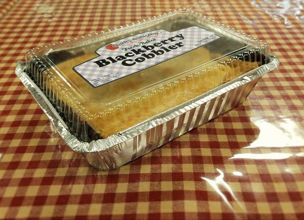 Image of a baked blackberry cobbler in a plastic container.